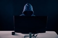 Anonymous and faceless hacker under hoodie using computer isolated over dark background - PhotoDune Item for Sale