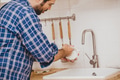 Man doing chores cleaning dishes cup at home kitchen sink holiday activity. - PhotoDune Item for Sale