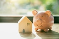 smile piggy bank with home wood house model morning sunlight background - PhotoDune Item for Sale