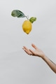 Tattooed hand throwing a lemon up in a gray sky - PhotoDune Item for Sale