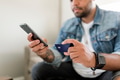 Man holding credit card and phone, sitting on a couch at home - PhotoDune Item for Sale