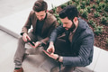 two businessman sitting outdoors using sharing tablet and smartphone - PhotoDune Item for Sale