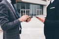 Two unrecognizable young elegant businessman outdoors using smartphone - PhotoDune Item for Sale