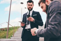 Two young elegant businessman outdoors using tablet and smartphone - PhotoDune Item for Sale
