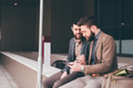 Two young contemporary businessman sitting outdoors using tablet - PhotoDune Item for Sale