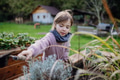 Little girl taking care of plants in garden, during first spring days. Concept of water conservation - PhotoDune Item for Sale
