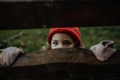 Portrait of little girl hiding behind wooden fence, looking between wooden boards. - PhotoDune Item for Sale