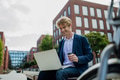 Businessman, freelancer or manager working outdoors in city park. Man with laptop on knees drinking - PhotoDune Item for Sale