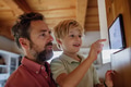 Boy helping father to adjust, lower heating temperature on thermostat. Concept of sustainable - PhotoDune Item for Sale