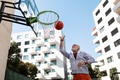 Senior man playing basketball outdoors on basketball court in city. Older, vital man has active - PhotoDune Item for Sale