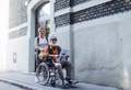 Granddaughter pushing senior man in wheelchair on street. Female caregiver and elderly man enjoying - PhotoDune Item for Sale