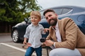 Close up of man and his little son holding power supply cable from their electric car. - PhotoDune Item for Sale
