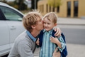Father saying goodbyeto to son in front of school building, hugging him and kissing him on the cheek - PhotoDune Item for Sale
