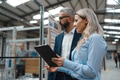 Female engineer and male production manager standing in modern industrial factory, talking about - PhotoDune Item for Sale
