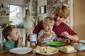 Family eating breakfast together in home kitchen. Healthy breakfast or snack before kindergarden - PhotoDune Item for Sale
