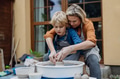 Mother teaching son how make pottery on pottery wheel. Child creative activities and art. Boy making - PhotoDune Item for Sale