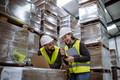 Warehouse manager talking and laughing with logistics employee in warehouse, planning transport of - PhotoDune Item for Sale