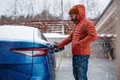 Man charging electric car during cold snowy day. Side view of hansome man putting charger in - PhotoDune Item for Sale