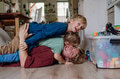Portrait of father embracing his two sons at home, having fun, lying on floor and laughing. - PhotoDune Item for Sale