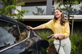 Young woman holding power supply cable from her electric car, prepared for charging it in home - PhotoDune Item for Sale