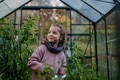 Little girl taking care of plants in greenhouse, during first spring days. Concept of water - PhotoDune Item for Sale