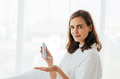 Attractive Caucasian female squeezing cream on hand and looking at camera while performing everyday - PhotoDune Item for Sale