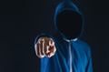 Anonymous and faceless man under hoodie pointing finger at camera isolated over dark background - PhotoDune Item for Sale