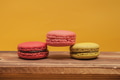 Pile of colorful macarons stacked up in yellow pastel isolated background on wood table - PhotoDune Item for Sale