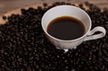 Cup of brewed espresso coffee on heap of dark coffee beans on wooden table. - PhotoDune Item for Sale