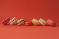 Set of colorful macaroons stacked on horizontal line in red pastel isolated background - PhotoDune Item for Sale