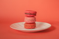 Pile of red-toned macaroons stacked up like a tower on white plate in red pastel isolated background - PhotoDune Item for Sale