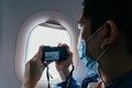 male tourist wearing a face mask inside aircraft cabin air and taking photos with a camera - PhotoDune Item for Sale