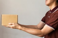 Delivery man giving a cardboard box on white background with copy space - PhotoDune Item for Sale