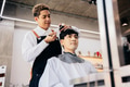 Happy young hairdresser trimming client hair - PhotoDune Item for Sale