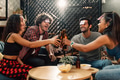 Friends clicking wine bottle while playing game at home in party - PhotoDune Item for Sale