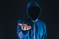 Anonymous and faceless man under hoodie giving a helping hand isolated over dark black background. - PhotoDune Item for Sale