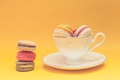 Pile of colorful macarons stacked up in the white classic cup in yellow pastel isolated background - PhotoDune Item for Sale