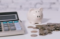 Money piggy bank with pile of cash coins and calculator - indicates money savings - PhotoDune Item for Sale