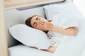 Sleepy Caucasian female with closed eyes covering mouth with hand and yawning while lying on - PhotoDune Item for Sale