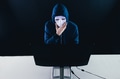 Anonymous and masked hacker under hoodie using computer isolated over dark background - PhotoDune Item for Sale