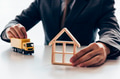 Businessman holding a miniature of house and delivery toy truck - PhotoDune Item for Sale