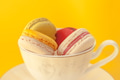 Pile of colorful macarons stacked up in the white classic cup in yellow pastel isolated background - PhotoDune Item for Sale