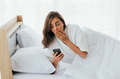 Amazed woman looking at smartphone on bed - PhotoDune Item for Sale