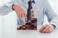 Close up of businessman using hand to climb up a stack of blocks towards house model - PhotoDune Item for Sale