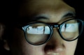 Young Asian man in glasses watching videos and surfing internet on technology device in the dark - PhotoDune Item for Sale