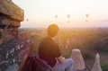 Silhouette of young male backpacker sitting and watching hot air balloon - PhotoDune Item for Sale