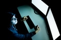 Hacker in mask under hood having many credit cards in computer room - PhotoDune Item for Sale