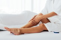 Caucasian female spreading smooth cream on soft legs skin while sitting on comfortable bed at home - PhotoDune Item for Sale