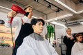 Male hairdresser using hairdryer on client - PhotoDune Item for Sale