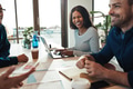 Laughing young businesswoman sitting with colleagues in an office - PhotoDune Item for Sale